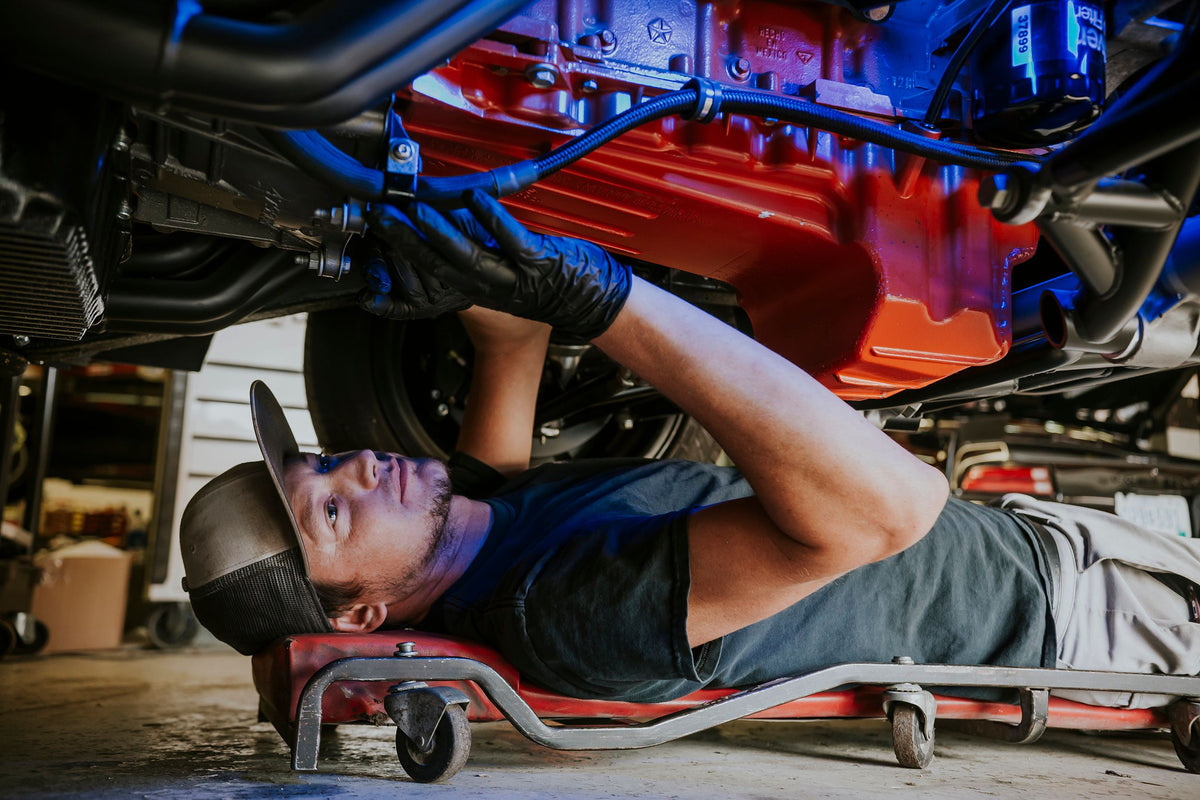 Mechanic installing brake lines under a vehicle